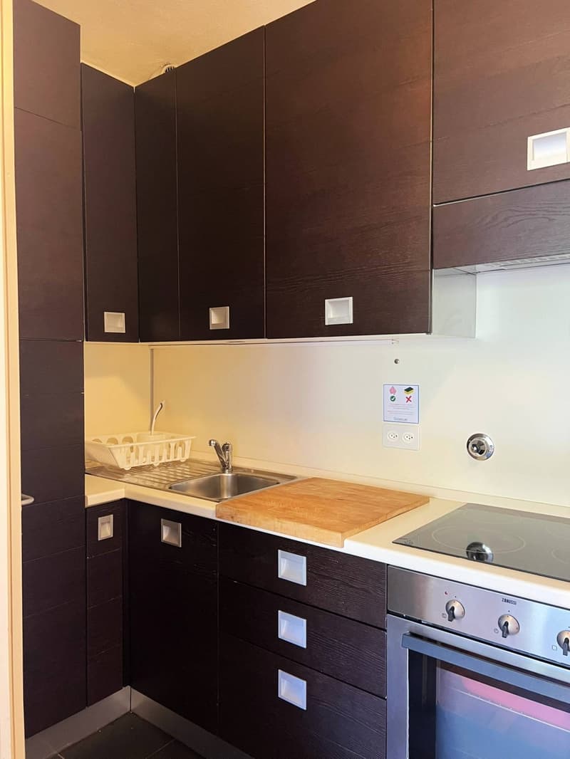 modern kitchen with dark wooden cabinets, stainless steel sink, gas stove, oven, dishwasher, power outlet, tiled floor