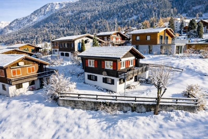 wooden chalet, snow covered, balcony, multiple houses, mountains in the background