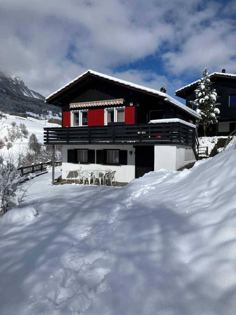 2 story chalet, red shutters, white walls, balcony, snow covered ground
