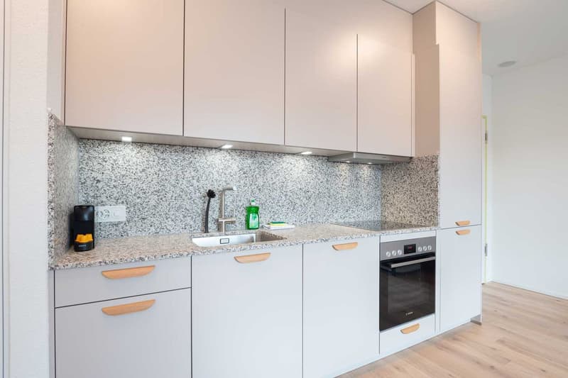 Modern kitchen with white cabinets, granite countertops, built-in oven, and dishwasher