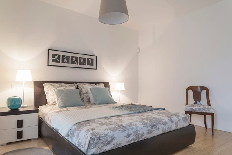 Bedroom with bed, nightstands, lamps, picture frame, wooden chair, rug