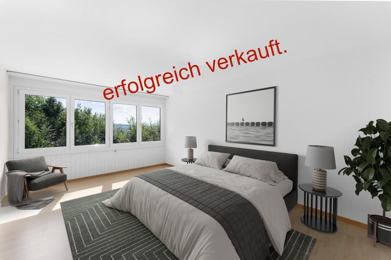 Modern bedroom with a double bed, large windows, gray furniture, white bedding, two lamps, a chair, and a rug, with a view of the trees outside.