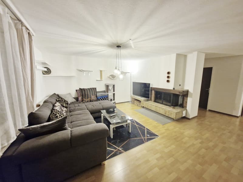 Living room with a fireplace, a large sofa, a coffee table, a TV, and a rug