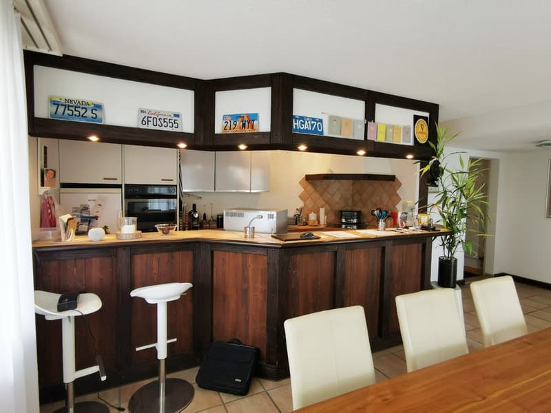 kitchen with island, wooden cabinets, white chairs, white bar stools, microwave, oven, sink, countertop, plant, license plates on wall