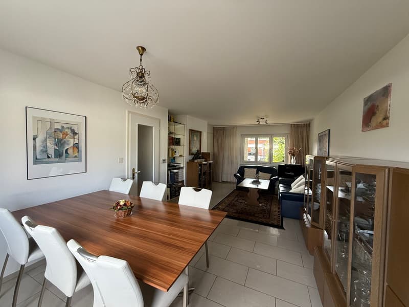 Dining room with wooden table, white chairs, chandelier, and decorative items