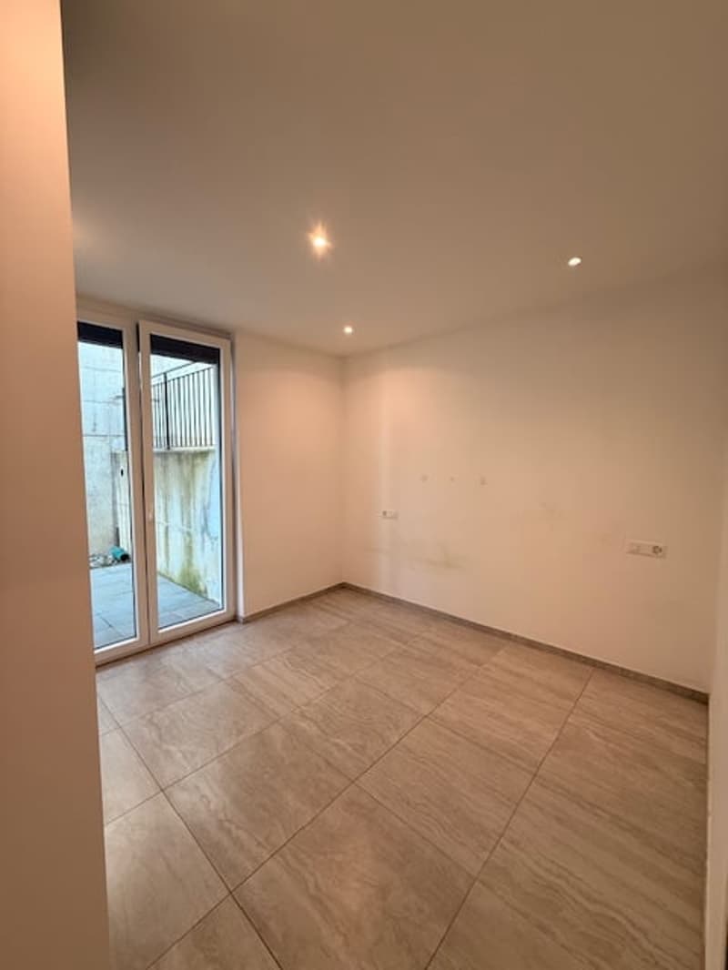 Empty room with sliding glass doors leading to balcony, tiled flooring, and recessed ceiling lights