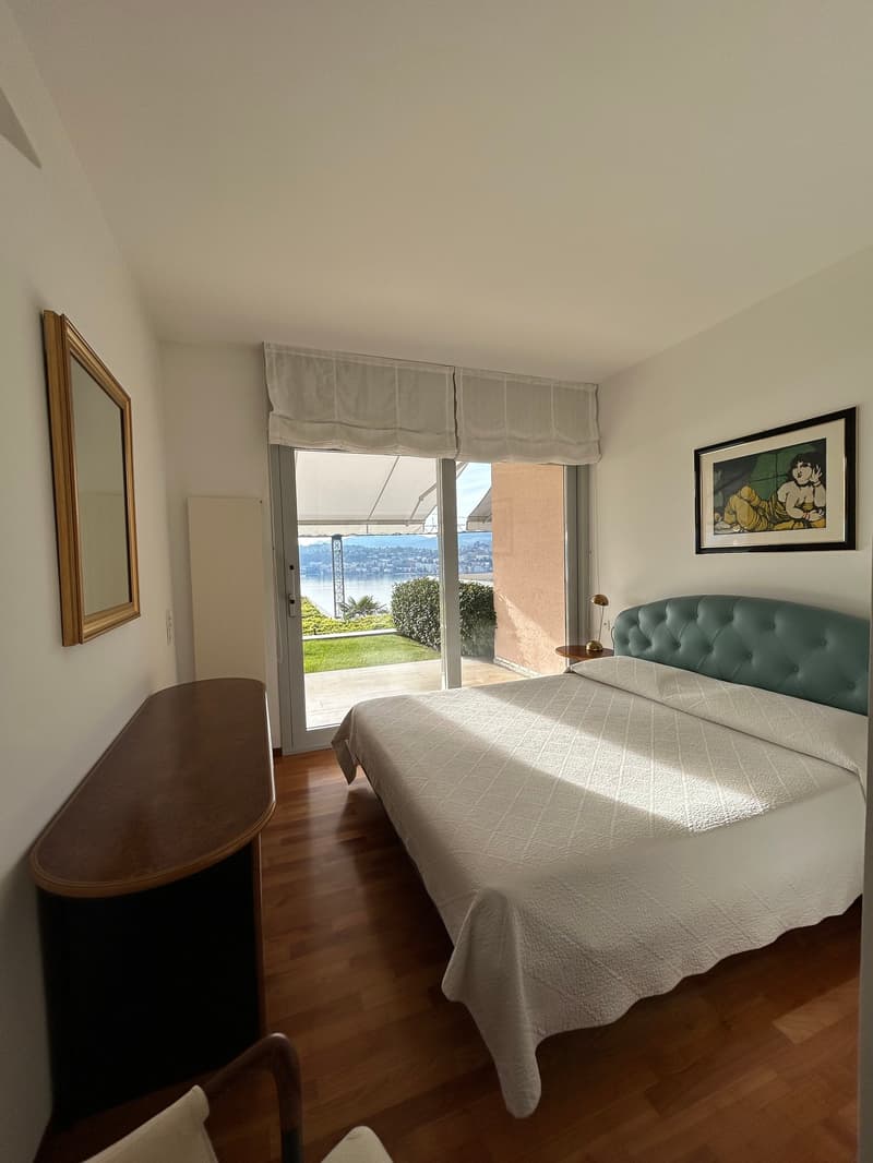 bedroom with bed, desk, mirror, picture frame, sliding glass door, balcony, lamp, chair