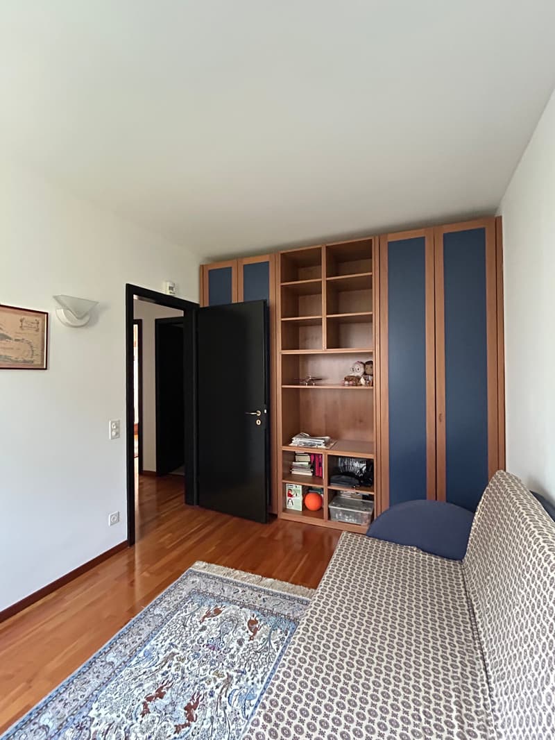 wooden floor, white walls, large couch, wooden shelf, open door, picture frame
