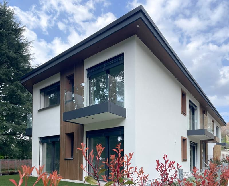 Modern 2 story house, white exterior, brown wooden accents, glass windows, balconies, green lawn