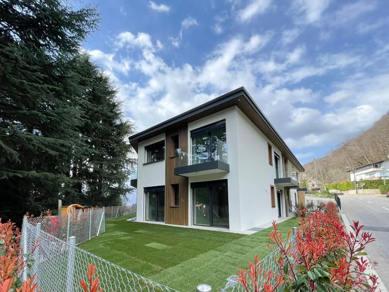 Modern 2-story house, white exterior, brown wooden accents, large glass windows, balcony, well-maintained lawn, chain-link fence