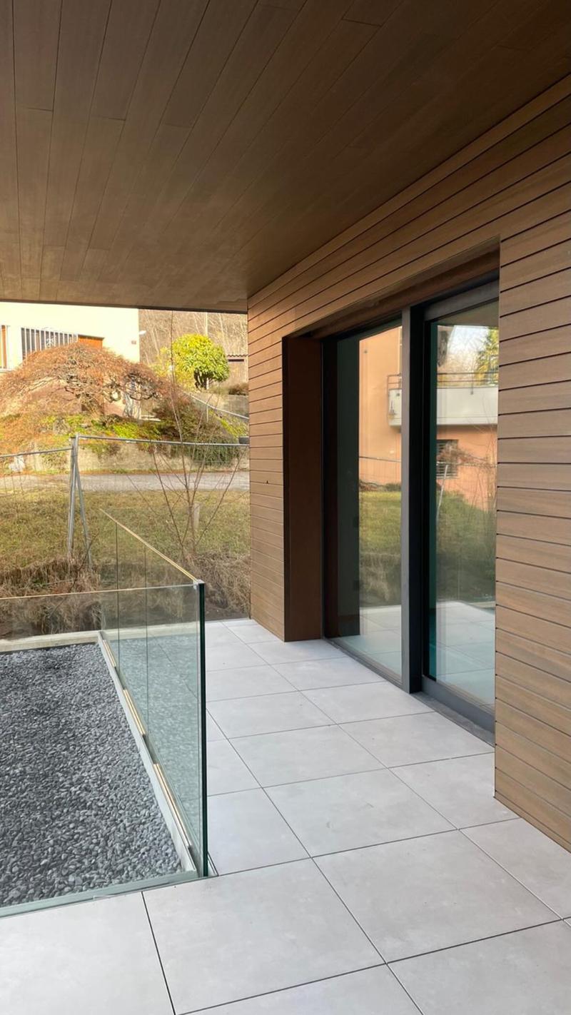Balcony with glass railing, wooden walls, and glass sliding doors