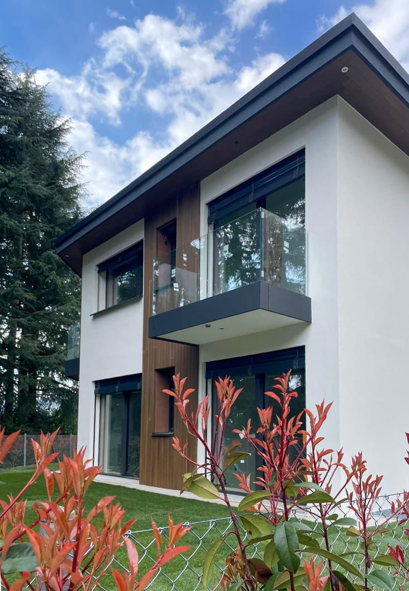modern house, white and brown exterior, glass windows, glass balcony, green lawn, fence