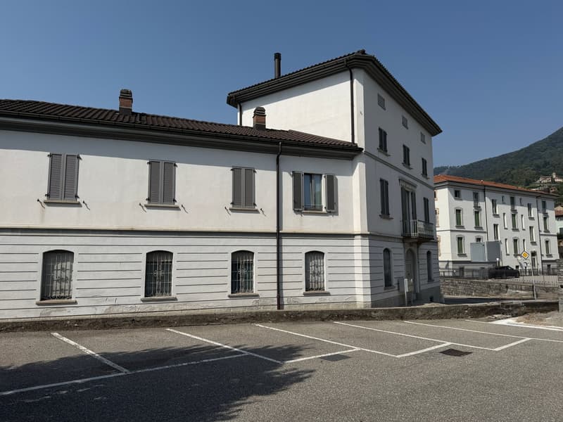white building, multiple windows, brown roof, parking lot in front