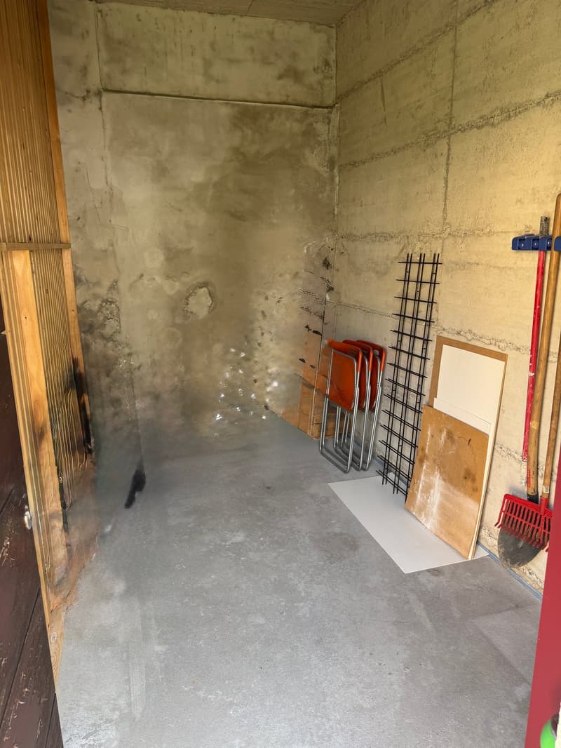 empty room, concrete floor, concrete walls, storage items, wooden door