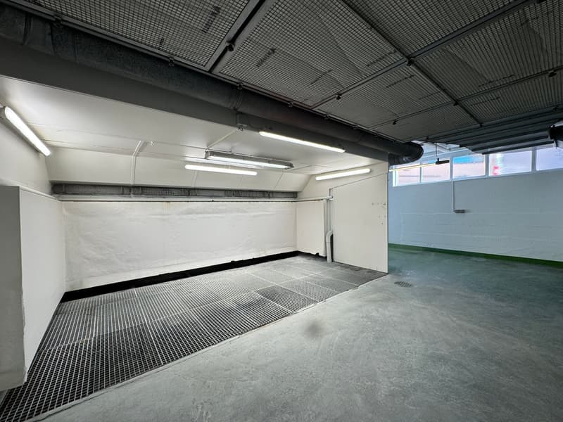 empty industrial room with metal floor and fluorescent lighting, white walls, small window on right side