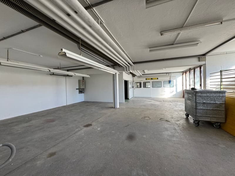 parking lot with concrete floor, metal poles, pipes, lights, doors, trash bin