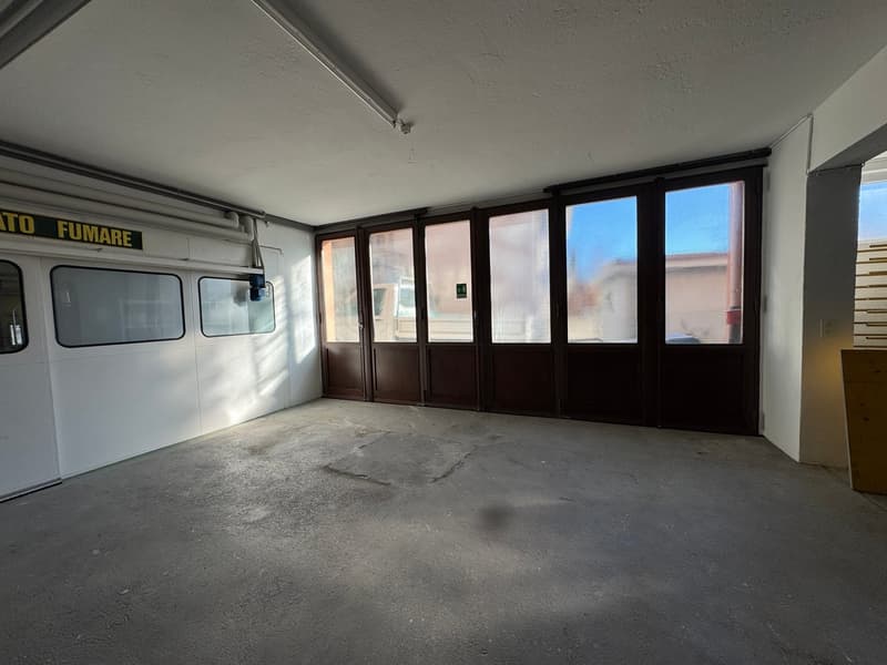 empty garage with white walls, large sliding windows, concrete floor, light fixture