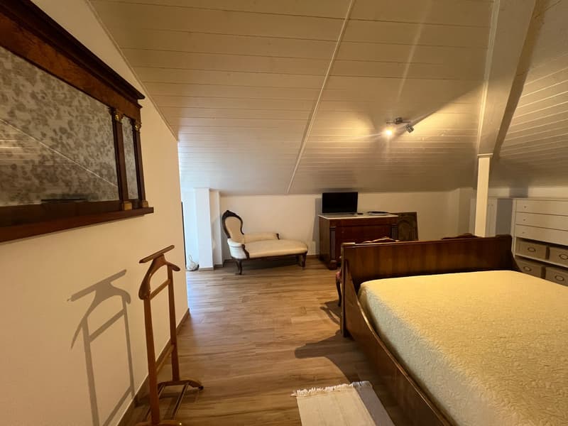 bedroom with wooden bed, chair, desk, TV, wardrobe, wooden floor, white walls