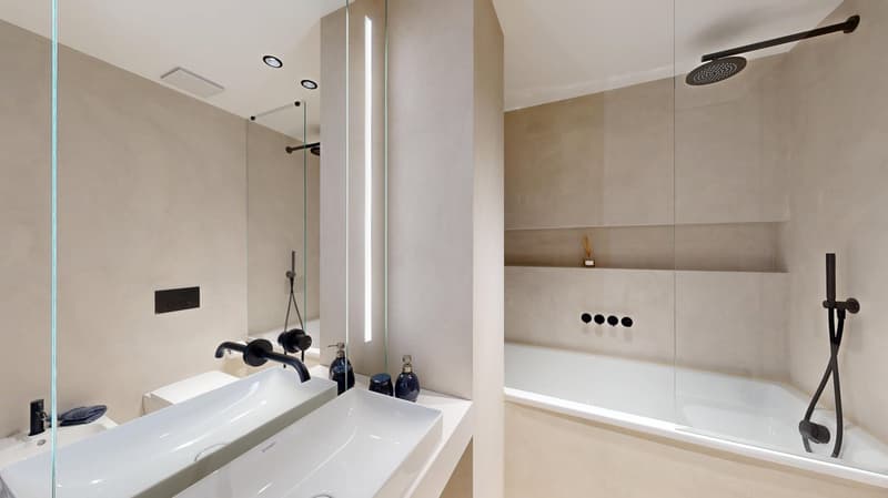 Modern bathroom with white walls, large vanity sink, black faucets, glass shower enclosure, and recessed lighting.