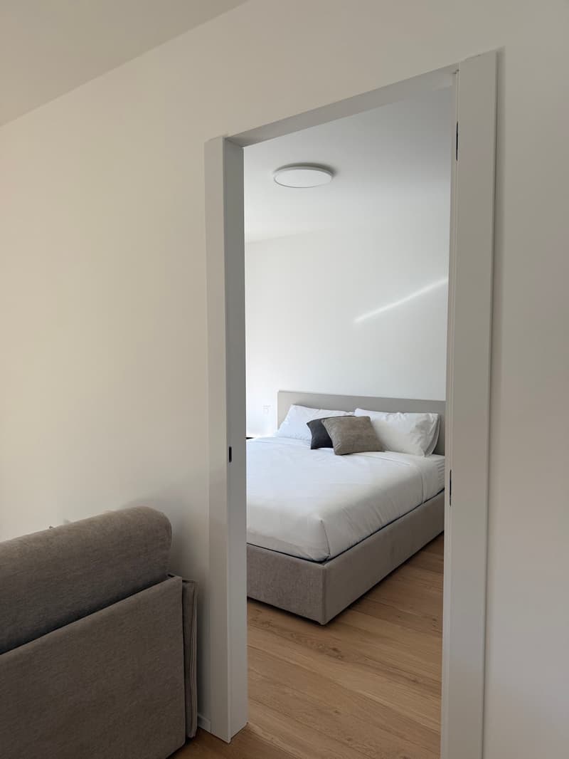 bedroom with bed and pillows, wooden floor, white walls