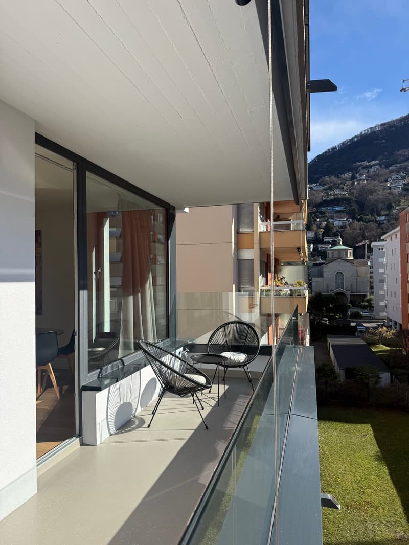 Large terrace with glass railings, outdoor seating, table, chairs, panoramic view, modern design, natural light, concrete floor