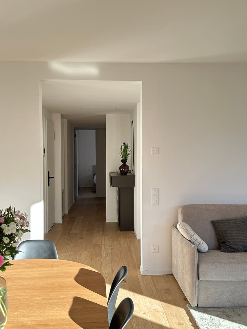Empty room with a small table, two gray chairs, sofa, and decorative items