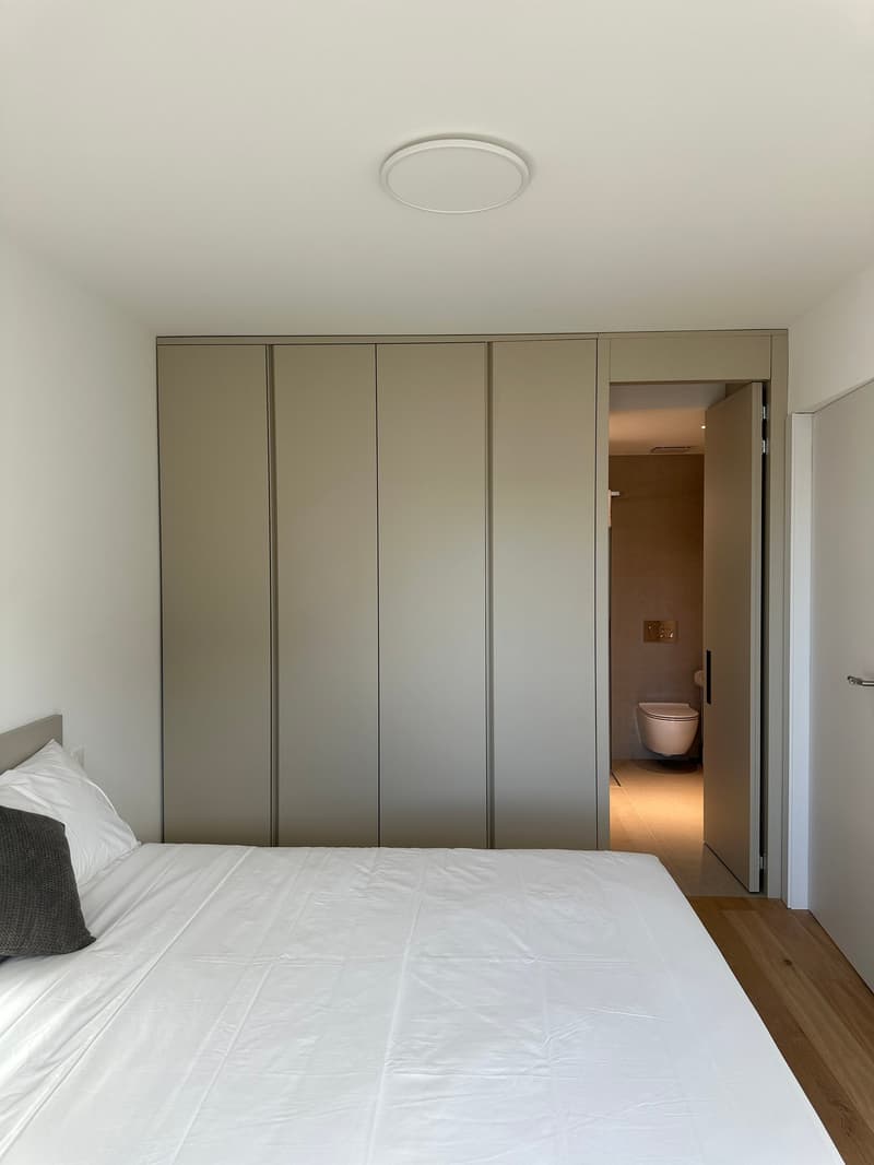 Bedroom with a double bed, a bedside table, a pillow, white linens, a walk-in closet, and a separate bathroom