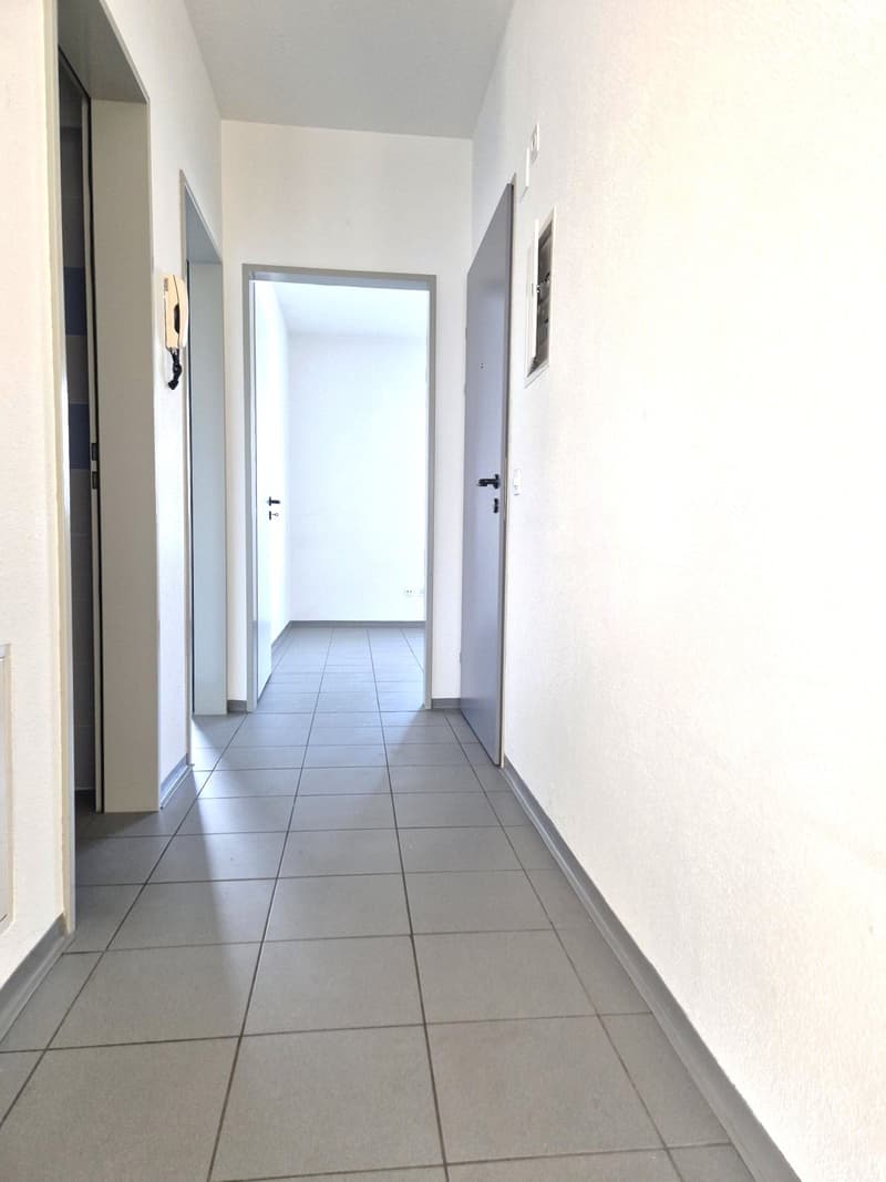 tiled hallway with two doors and telephone mounted on the wall
