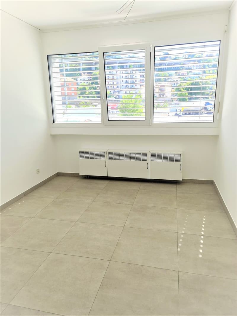 empty room, white walls, tiled floor, 3 windows with shutters, heating units