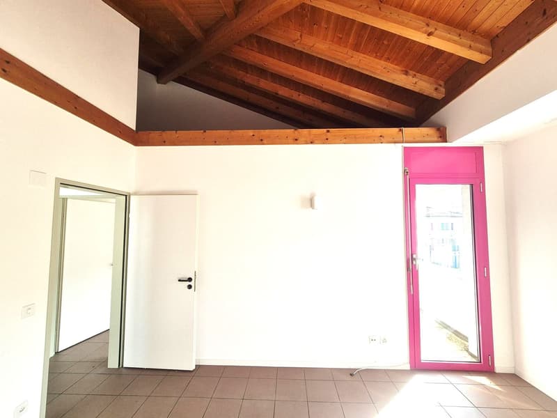 open space room, exposed wooden beams, two doors, large window, tiled floor