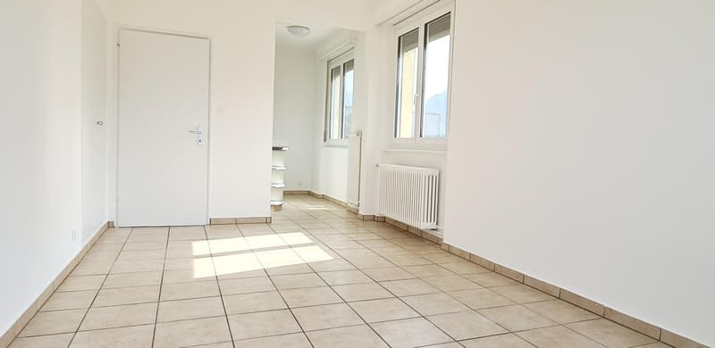 Empty room, tiled floor, two white radiators, double windows, white door