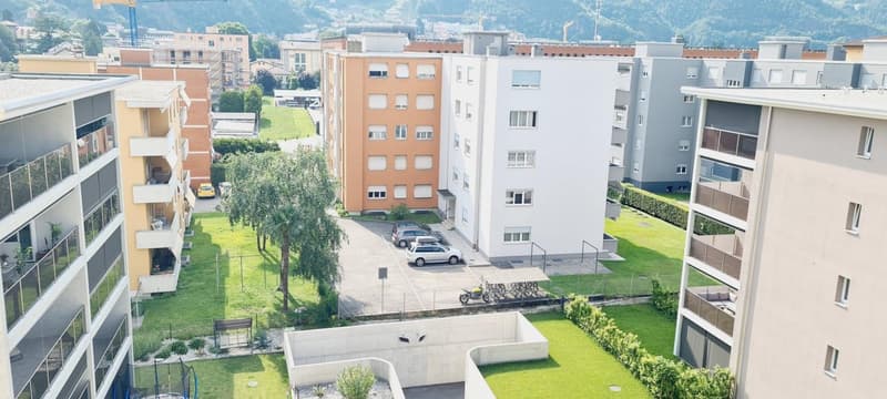 Urban area with residential buildings, parking area with multiple cars, common garden area