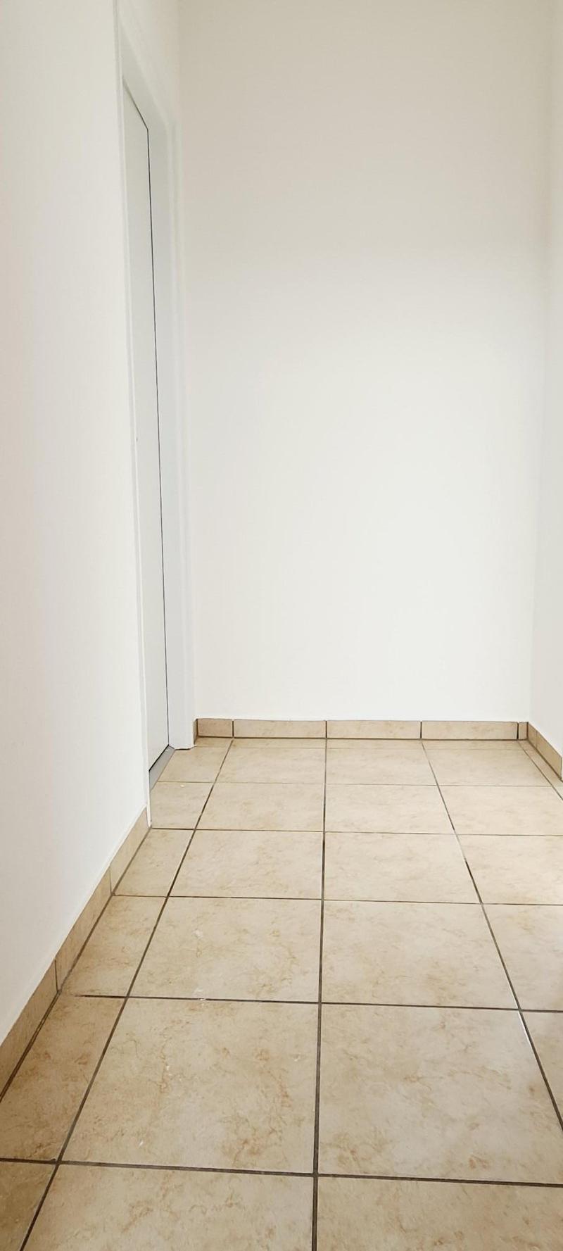 Empty room with white walls and tiled flooring