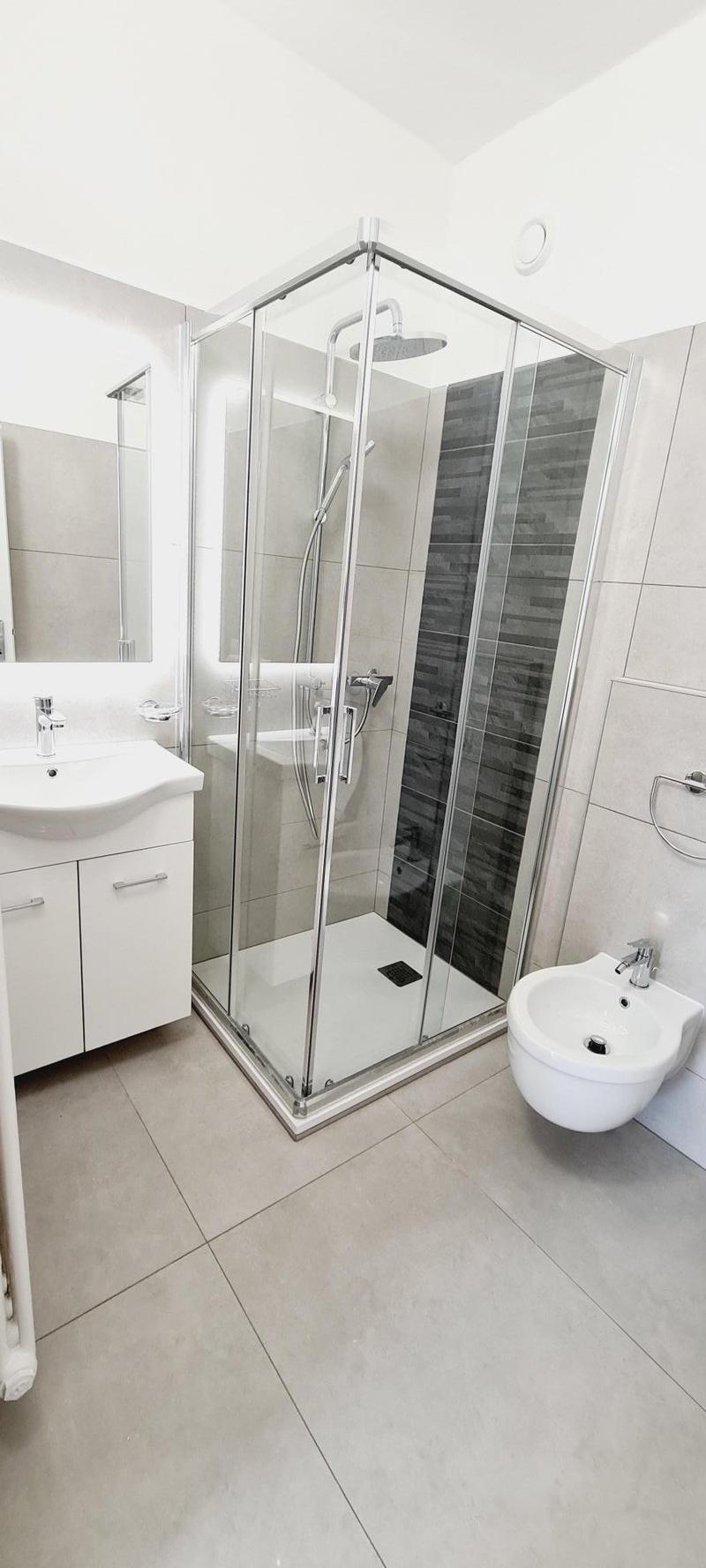 Modern bathroom with glass shower enclosure, white sink and wall-mounted toilet