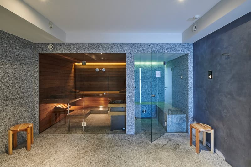 Sauna room with wooden benches, glass doors, and a shower area with blue tiles