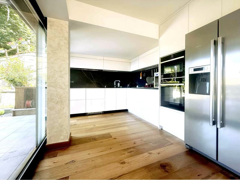 modern kitchen with wooden floor, white cabinets, black marble countertop, stainless steel appliances, glass door