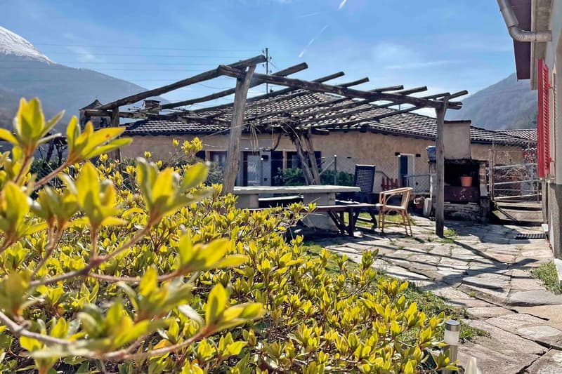 Mountain house, stone roof, wooden pergola, wooden tables and chairs, garden