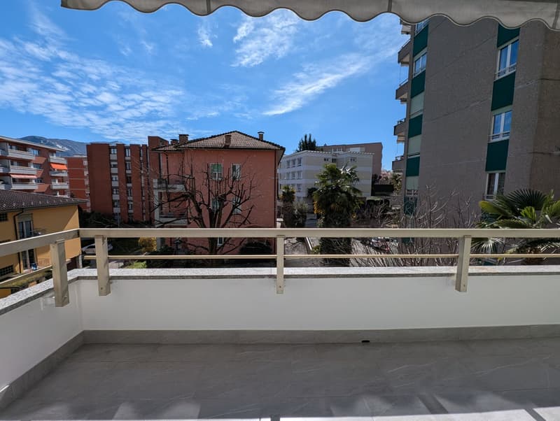 Balcony with metal railings, tiled floor, view of the city and mountains