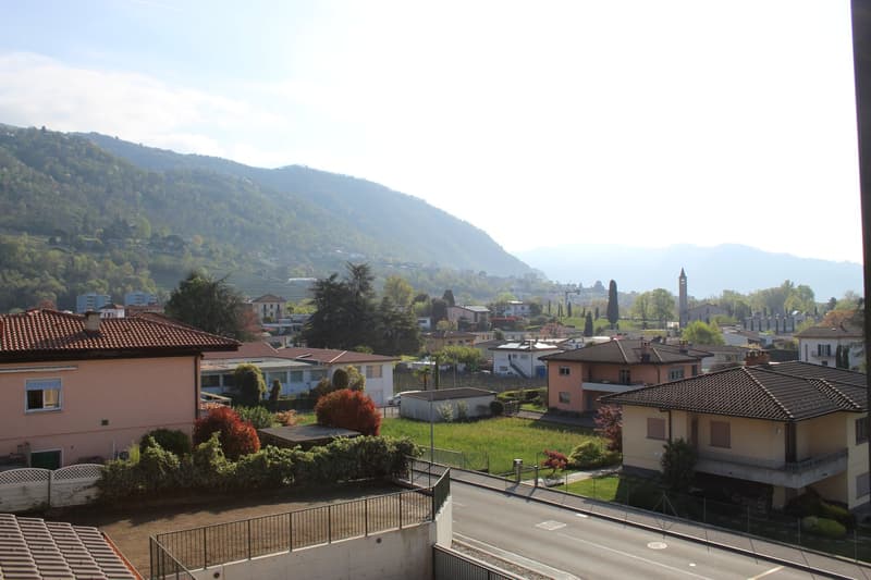 Aerial view of a neighborhood with several houses, mountains in the background, and a road.