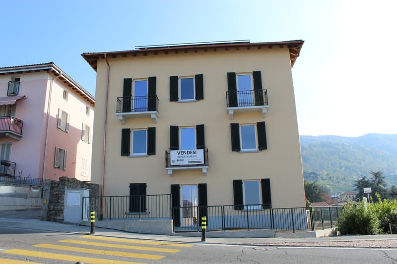 3 story building, beige exterior, black shutters, balconies, solar panels on roof