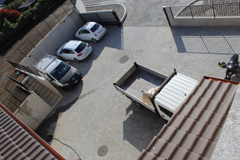 Aerial view of a parking area with three cars parked and a truck with an open back door.
