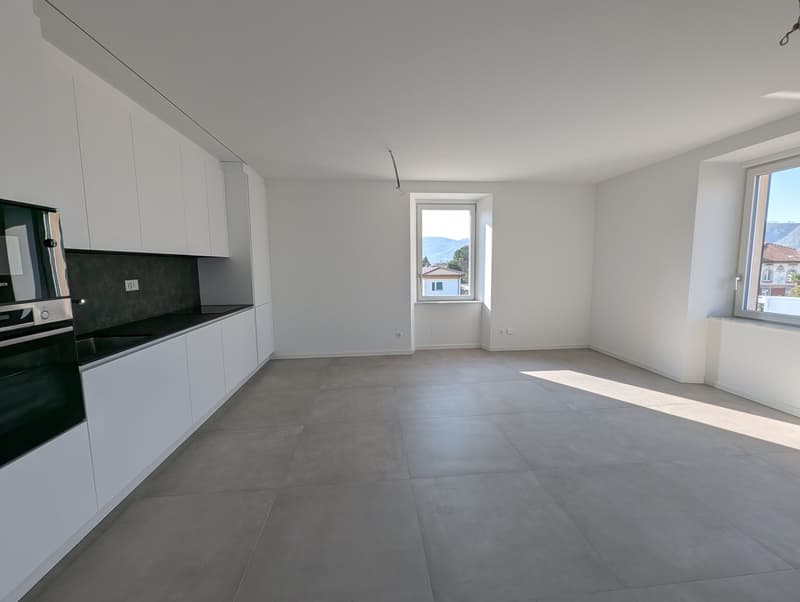 Empty kitchen with white cabinets, black countertops, oven, and windows with view