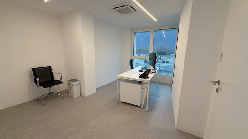 Office with gray floor, white walls, desk, computer, chair, window
