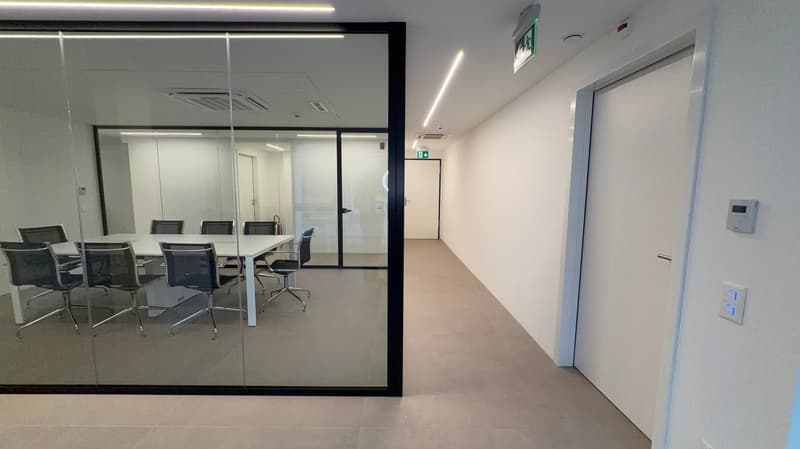 empty meeting room with glass walls and chairs around a table