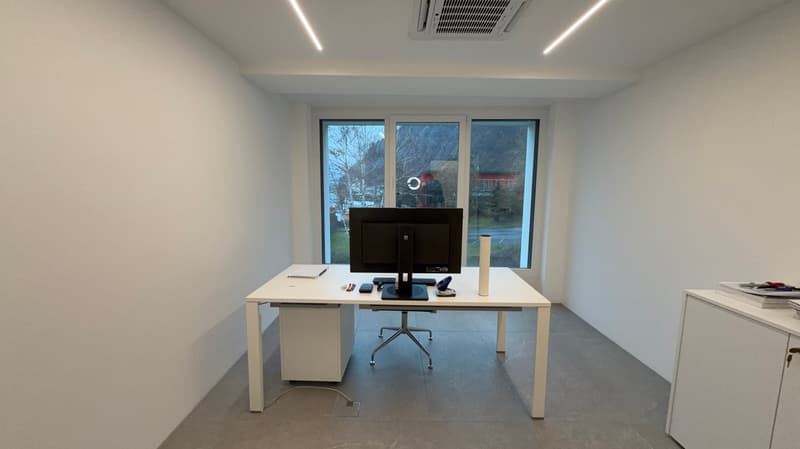 Minimalist office with a desk, computer, monitor, keyboard, and office chair. There are windows that allow natural light and an external view.