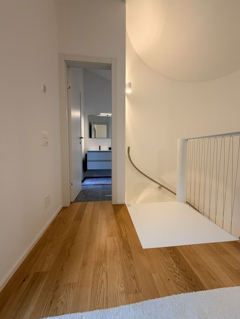 wooden floor, white walls, arched ceiling, modern open stairs, bathroom visible through door