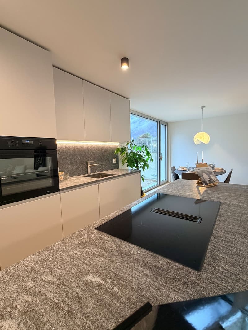 modern kitchen with kitchen island, black oven, stainless steel sink, countertop, natural light