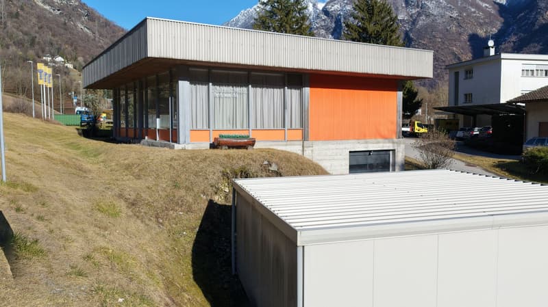 2 story modern house with orange and grey walls, large windows, sloped ground, large grass field, mountain view