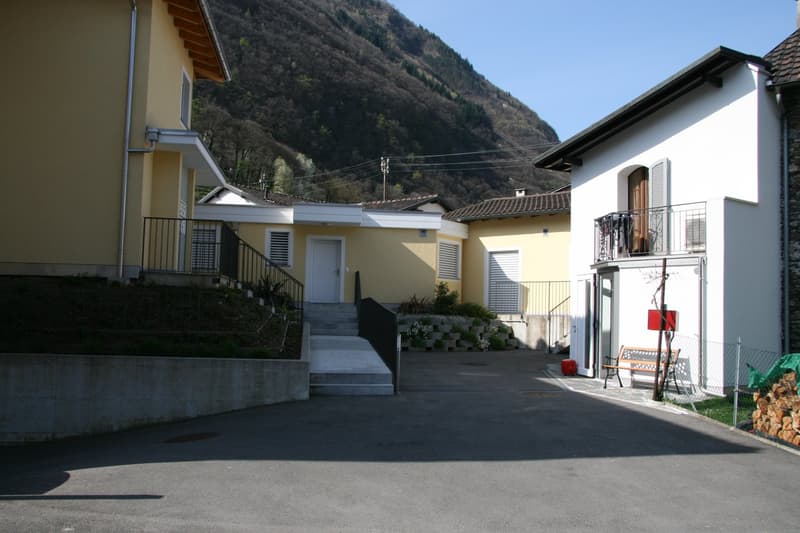 3 houses, yellow and white, raised ground floor, mountain in the background