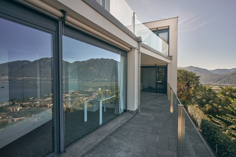 Glass balcony with metal railing, view of mountains and city